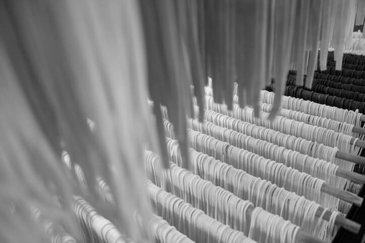 A black and white photo of long spaghetti strands hanging to dry