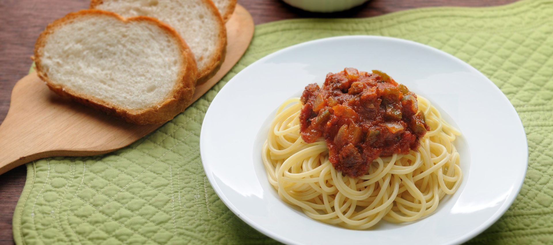 Spaghetti with Italian red sauce with onions and bell peppers and a side of bread