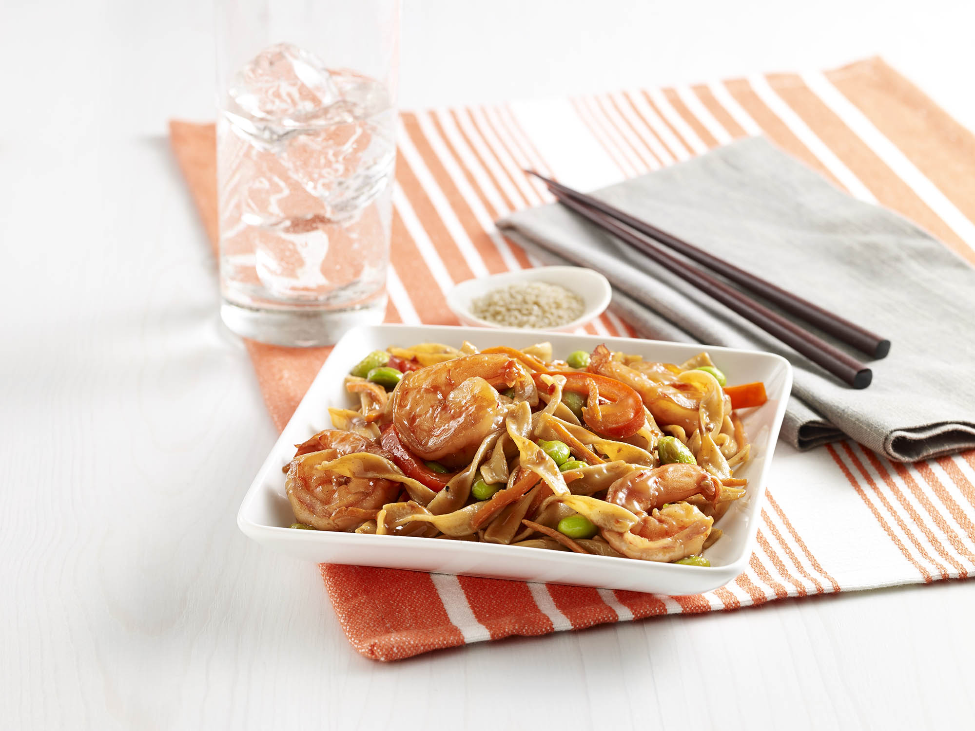 Egg noodles with shrimp, carrots, bell pepper, and edamame in a light soy sauce