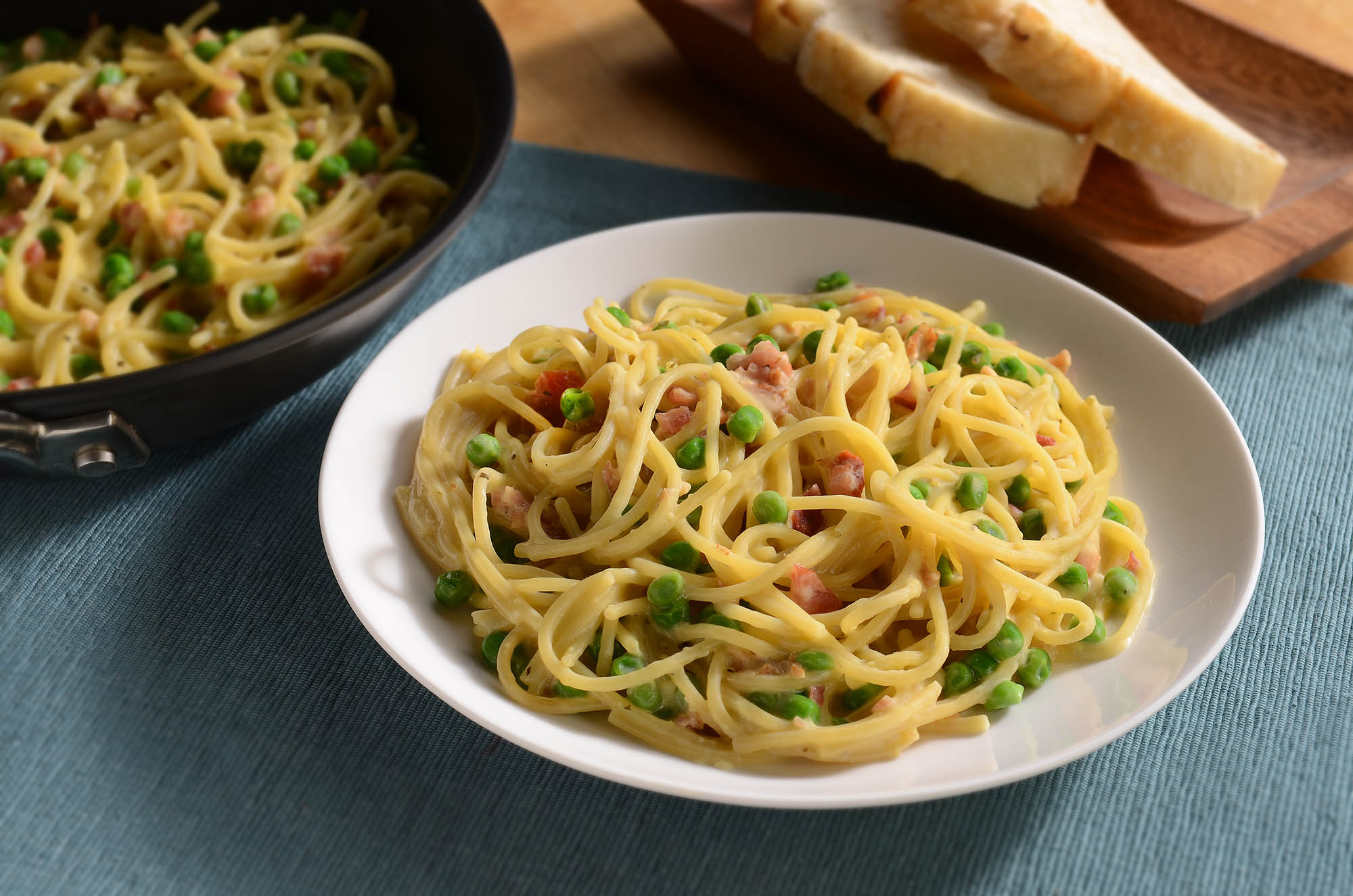 Linguine with crispy bacon and peas in a creamy sauce, topped with Parmesan cheese