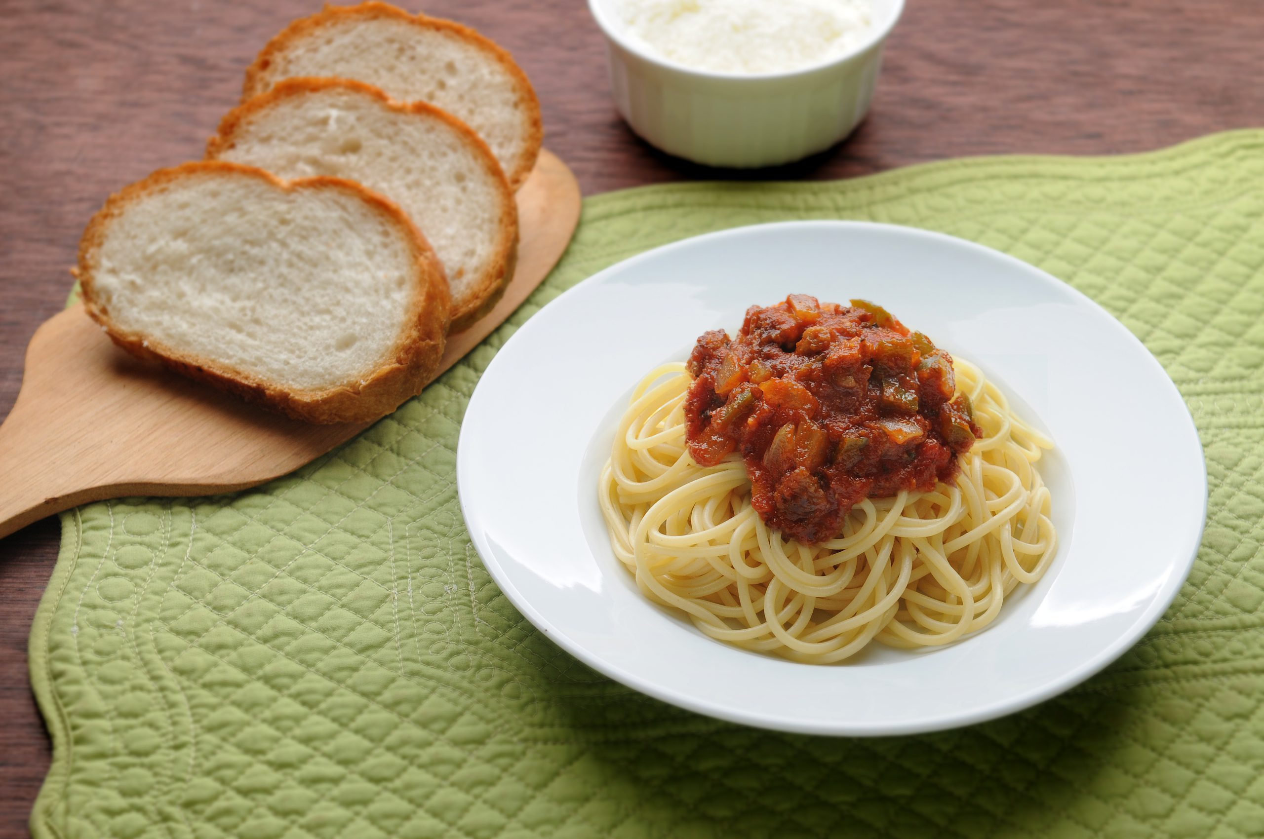 Spaghetti with Italian red sauce with onions and bell peppers and a side of bread